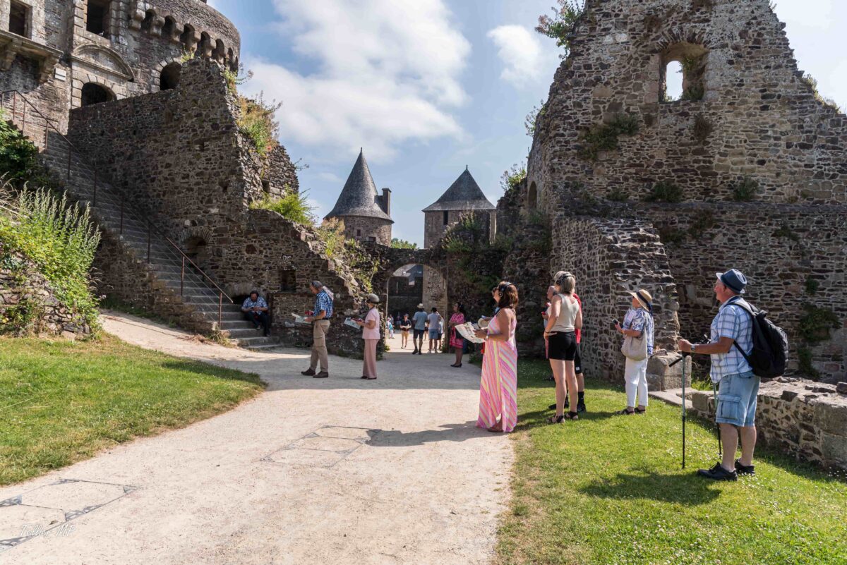 Des visiteurs qui écoutent l'audioguide dans la basse-cour du Château